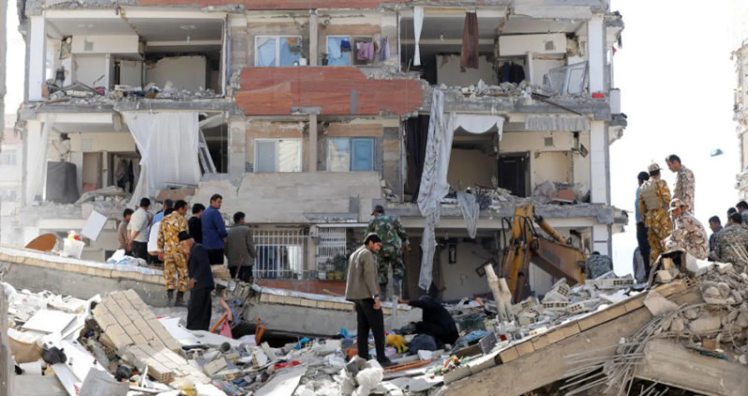 ناجون من الزلزال الذي ضرب الليلة قبل الماضية غرب إيران يبحثون عن متعلقاتهم في مجمع سكني حكومي حديث في سربل - ذهاب بمحافظة كرمانشاه أمس (إ.ب.أ)