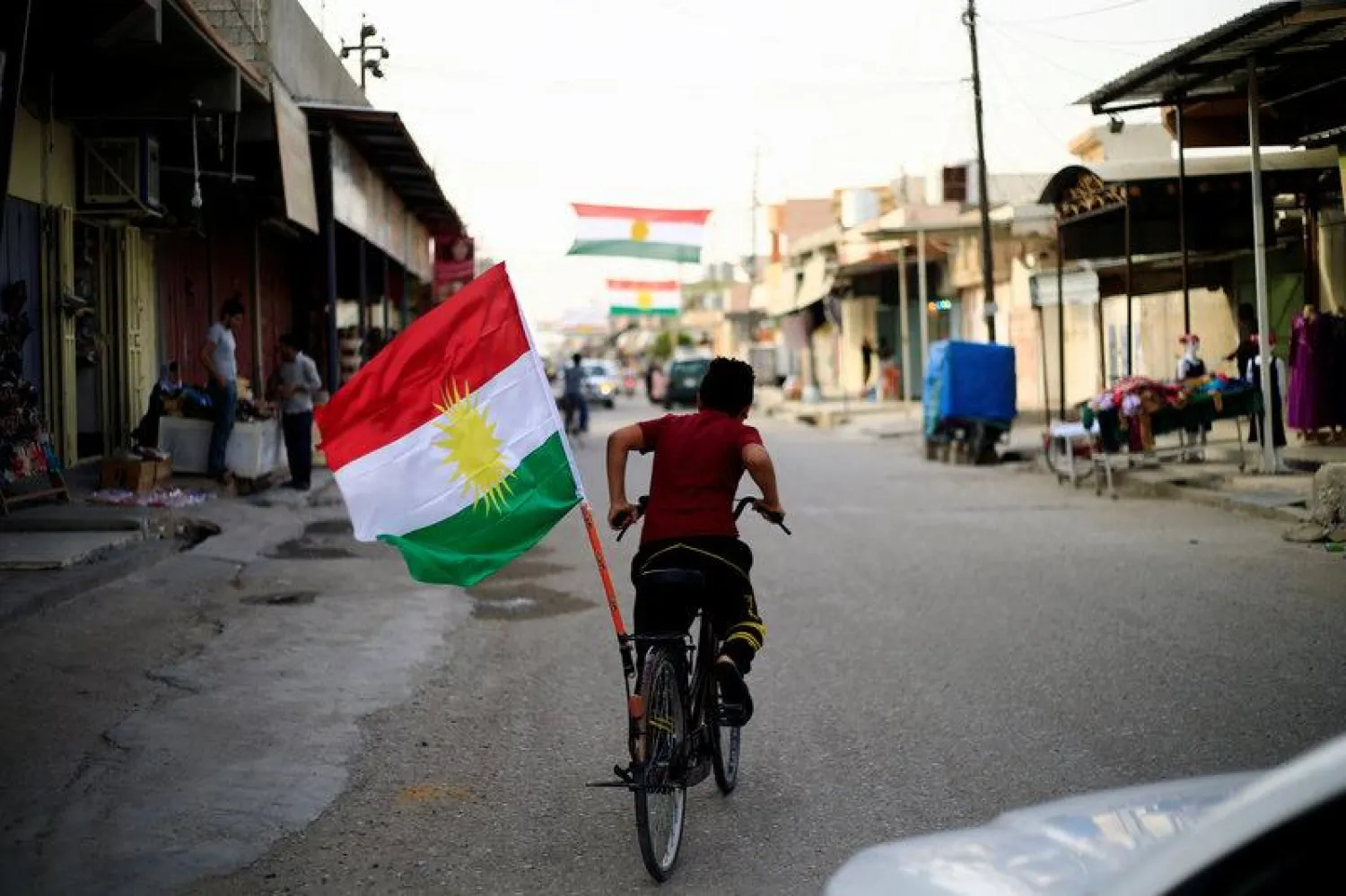 A boy rides a bicycle with the flag of Kurdistan in Tuz Khurmato, Iraq September 24, 2017. REUTERS/Thaier Al-Sudani