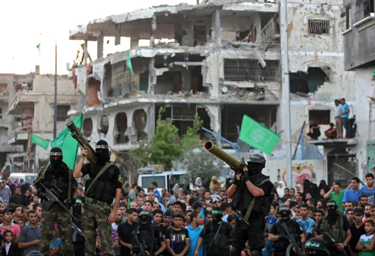 Palestinian fighters of the Ezz Al-Din Al Qassam militia, the military wing of Hamas, pose with weapons between a destroyed houses in Al-Shejaeiya neighborhood in the east of Gaza City, 27 August 2014. EPA