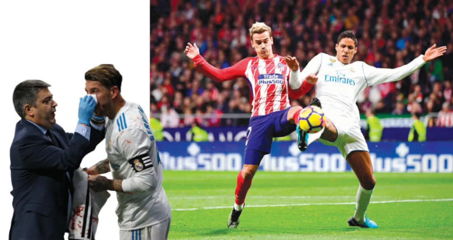 فاران مدافع الريـال (يمين) في صراع على الكرة مع غريزمان مهاجم أتلتيكو (أ.ف.ب)  -  راموس قائد الريـال أصيب بكسر في أنفه (أ.ب)