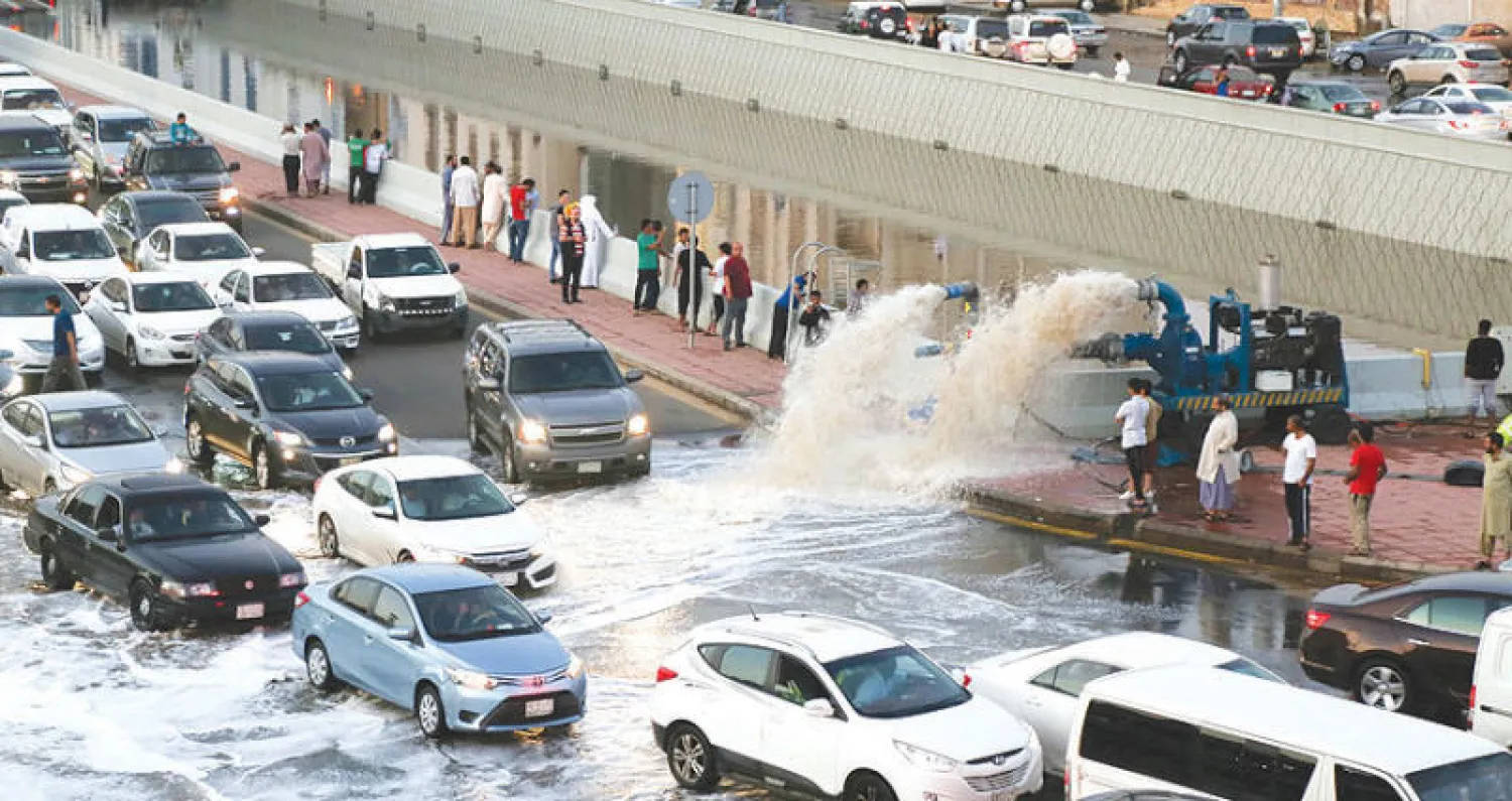 تسببت سيول جدة في إرباك حركة المرور في المدينة .. وفي الإطار رجل يقف على رصيف أحد الشوارع الغارقة (تصوير عدنان مهدلي-محمد المانع)
