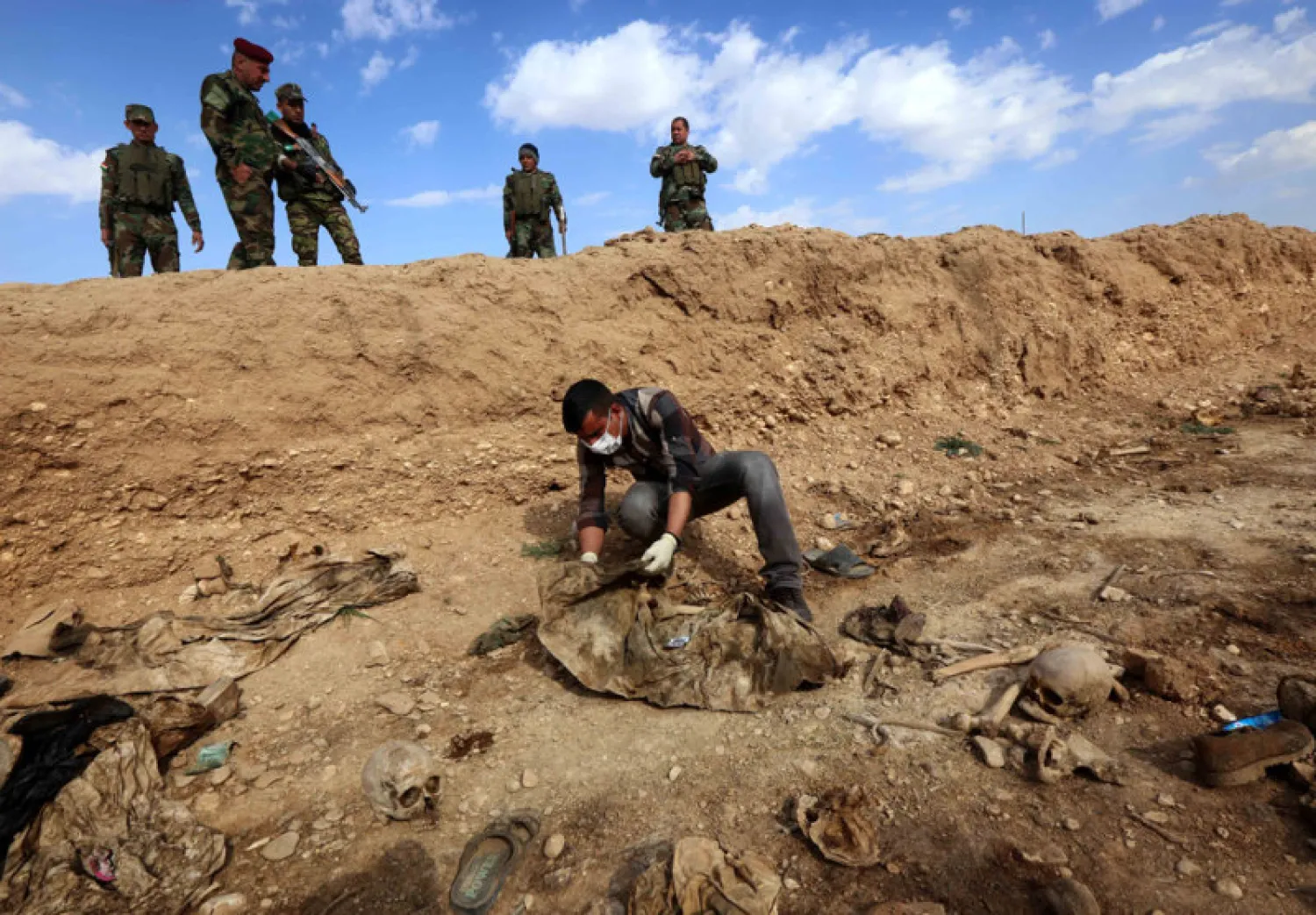 An Iraqi inspects the remains of Yazidis killed by ISIS jihadist group near the village of Sinuni, in the northwestern Sinjar area on February 3, 2015. AFP