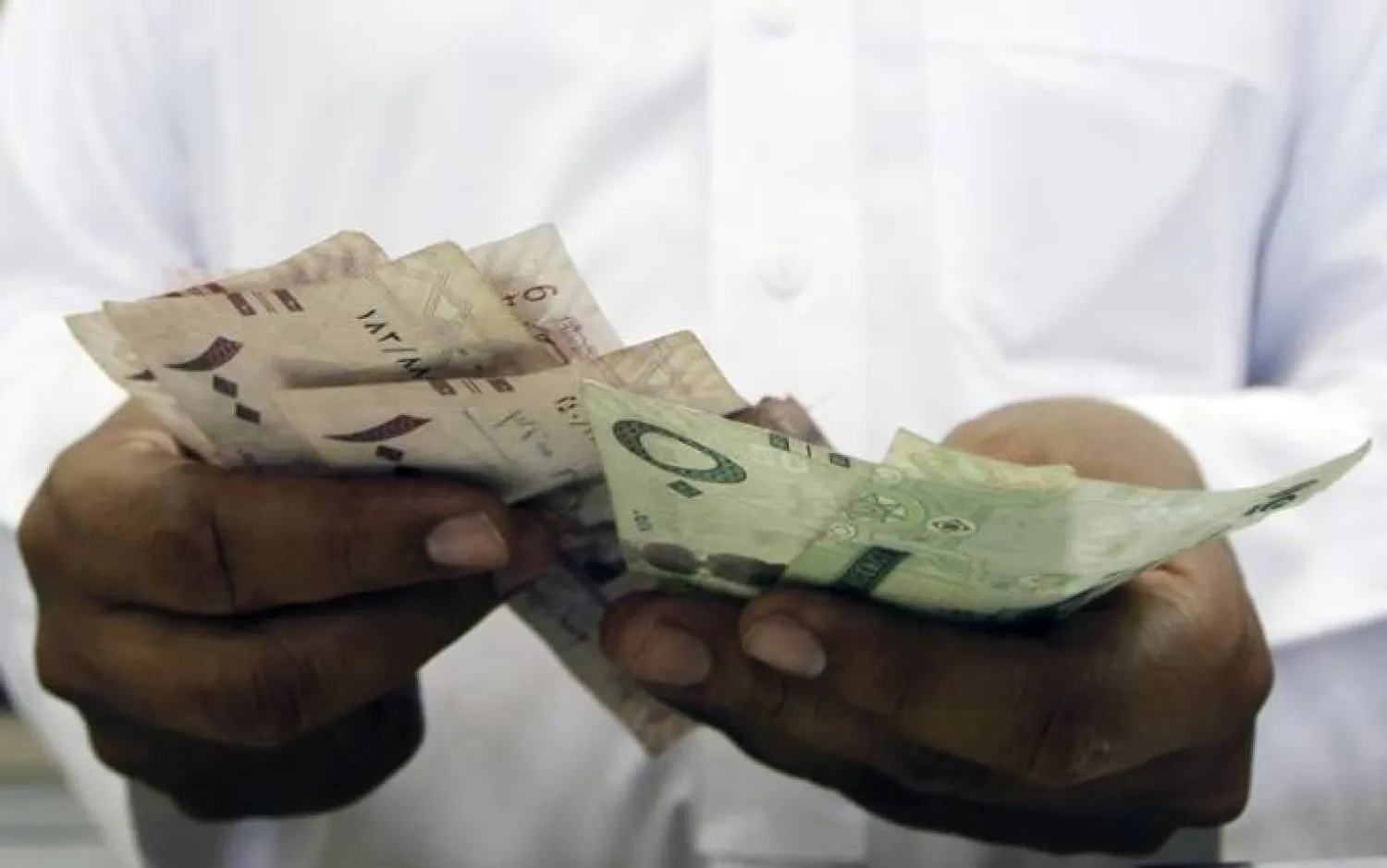 A Saudi jeweller counts Saudi Riyal banknotes money after selling gold to a customer in a jewellery shop at the surrounding area of the Grand Mosque during the annual haj pilgrimage in the holy city of Mecca. Reuters. 
