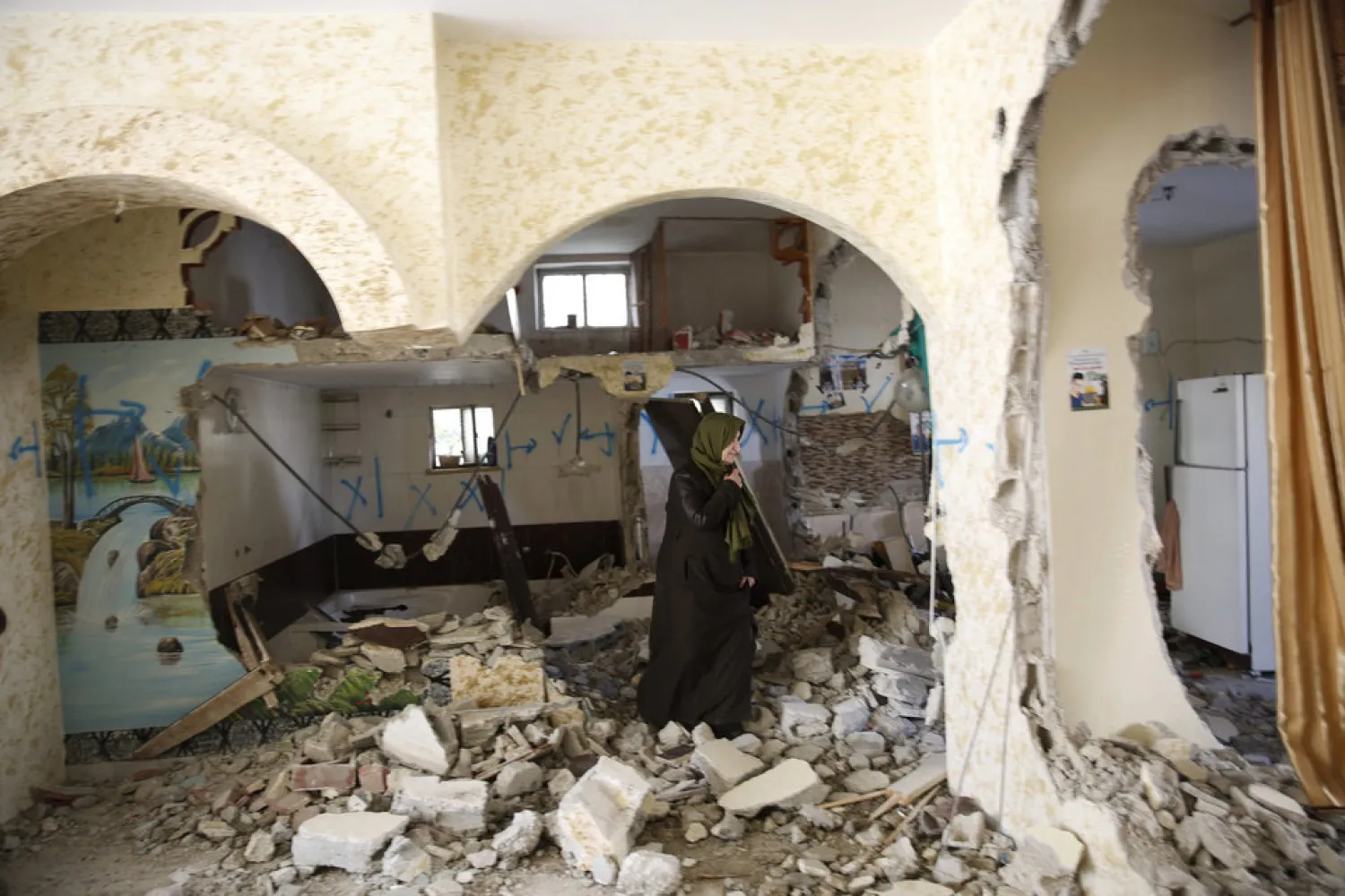 FILE - In this March 31, 2016 file photo, a Palestinian woman inspects a home that was demolished by the Israeli army in the West Bank city of Hebron. (AP Photo/ Nasser Shiyoukhi, File)