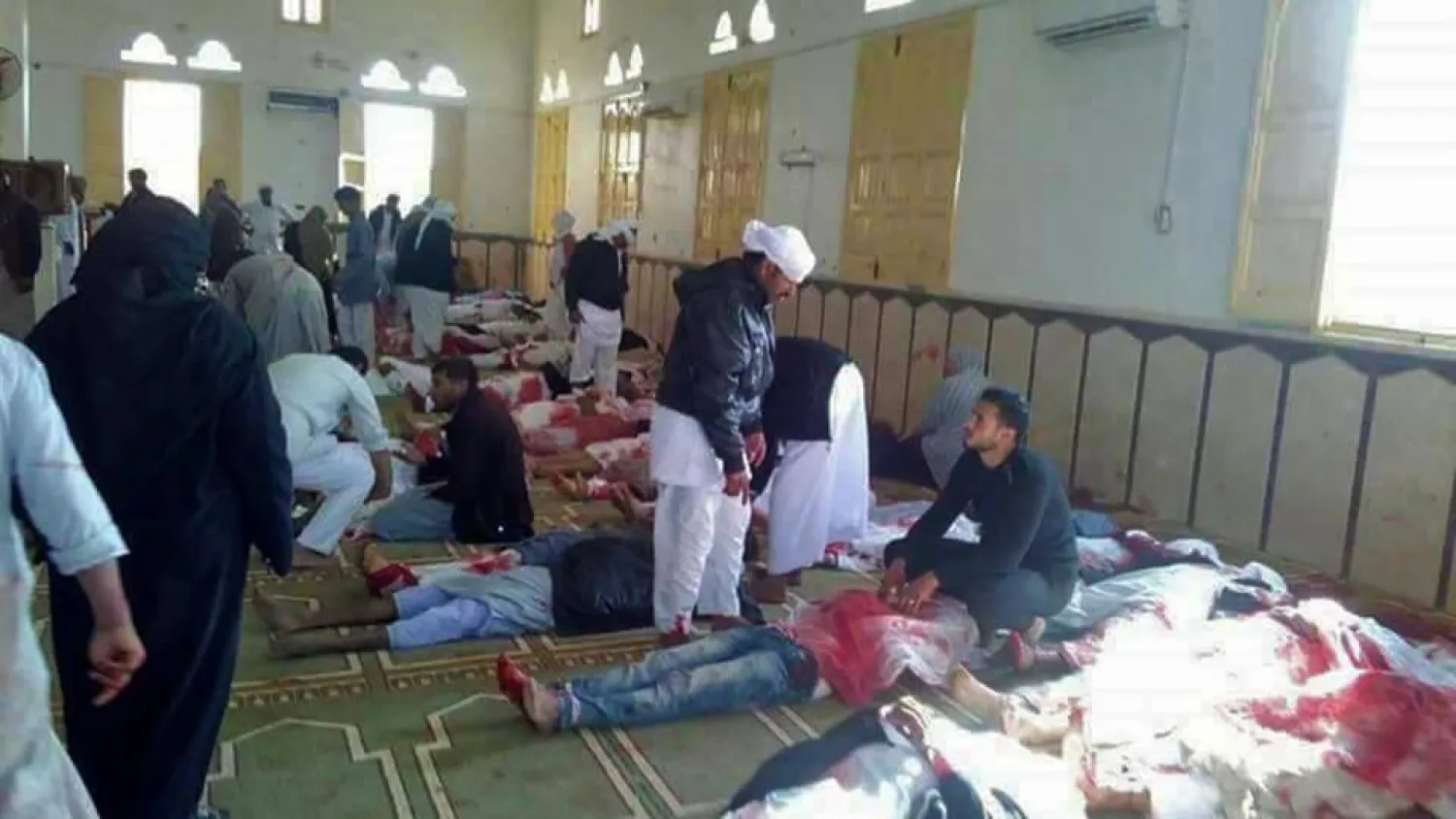 Egyptians walk past bodies following a gun and bombing attack at the al-Rawda mosque, west of the North Sinai capital of el-Arish, on November 24, 2017. (AFP)