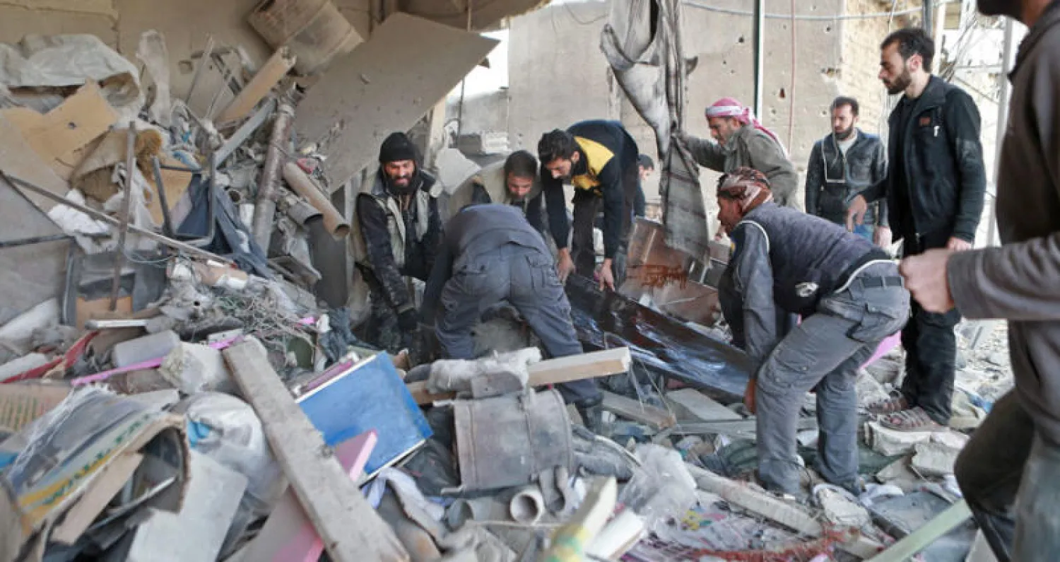 الدفاع المدني يحمل ضحايا خارج الركام بعد قصف عنيف على الغوطة الشرقية لدمشق أمس (أ.ف.ب)