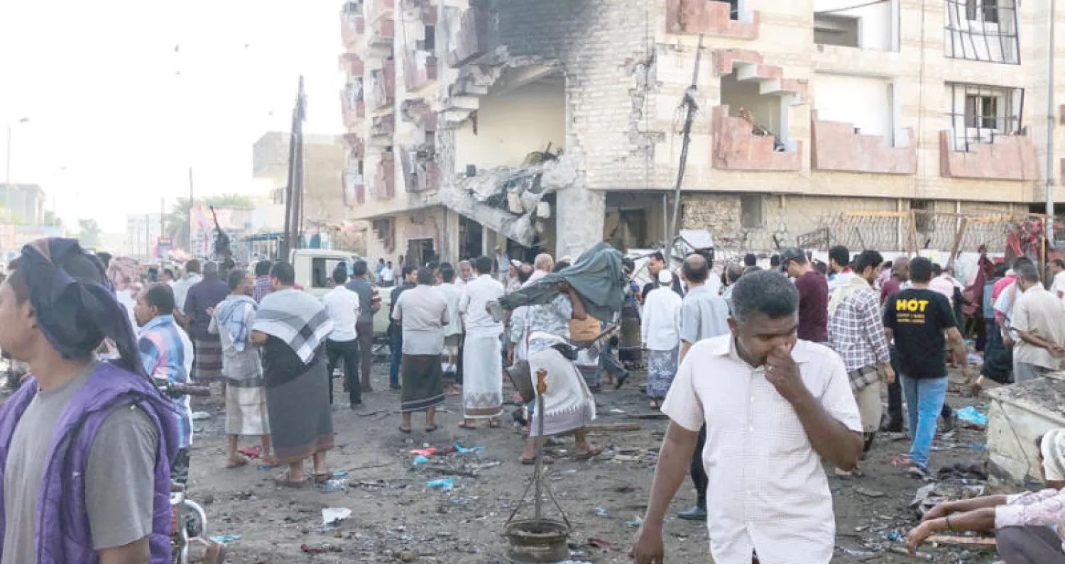 يمنيون يعاينون موقع التفجير الانتحاري الذي استهدف صباح أمس مبنى وزارة المالية في عدن (أ.ف.ب)