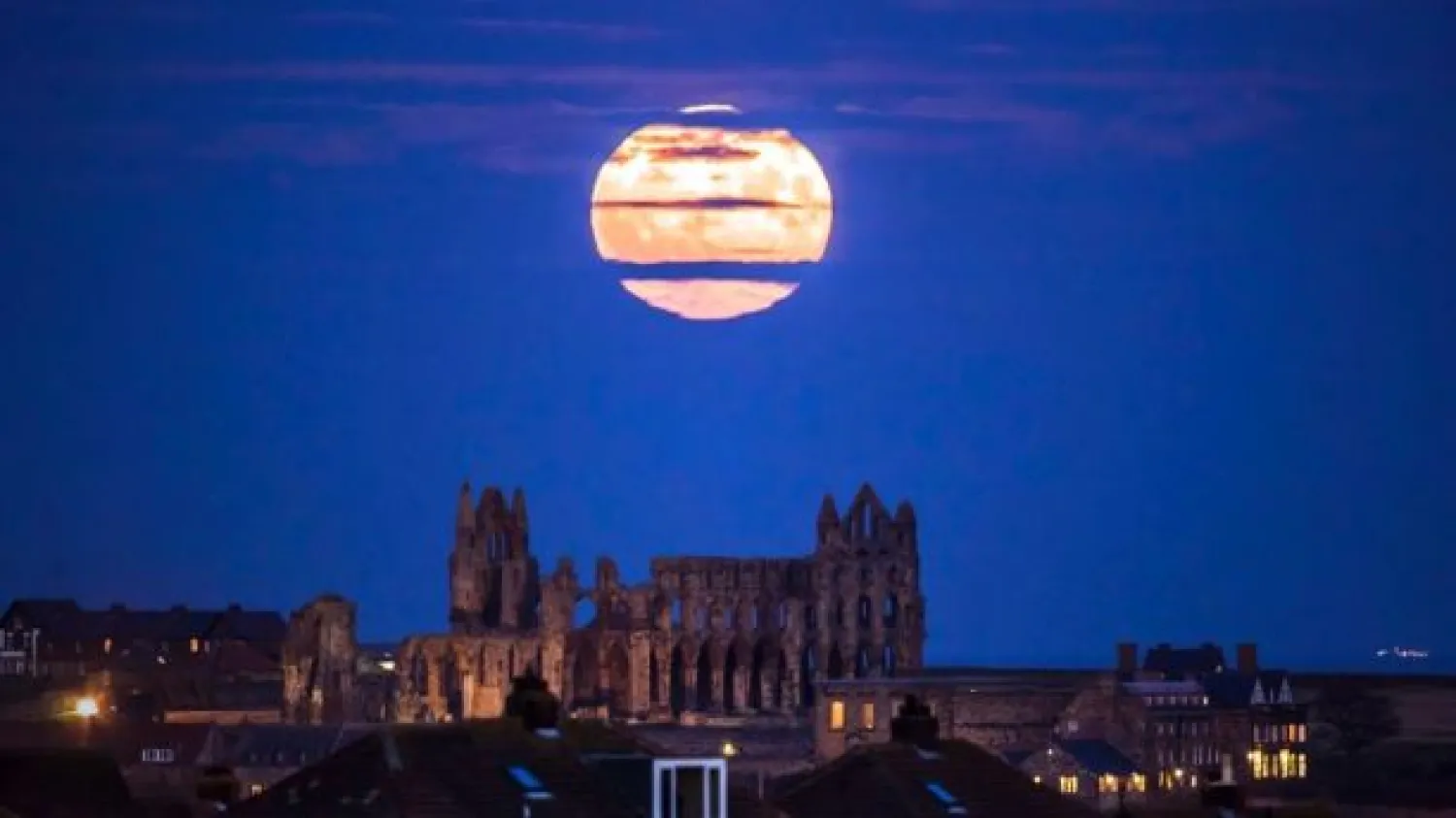 The supermoon rises above Whitby Abbey in Whitby, northeast England, on Sunday.  (Danny Lawson/PA via AP)