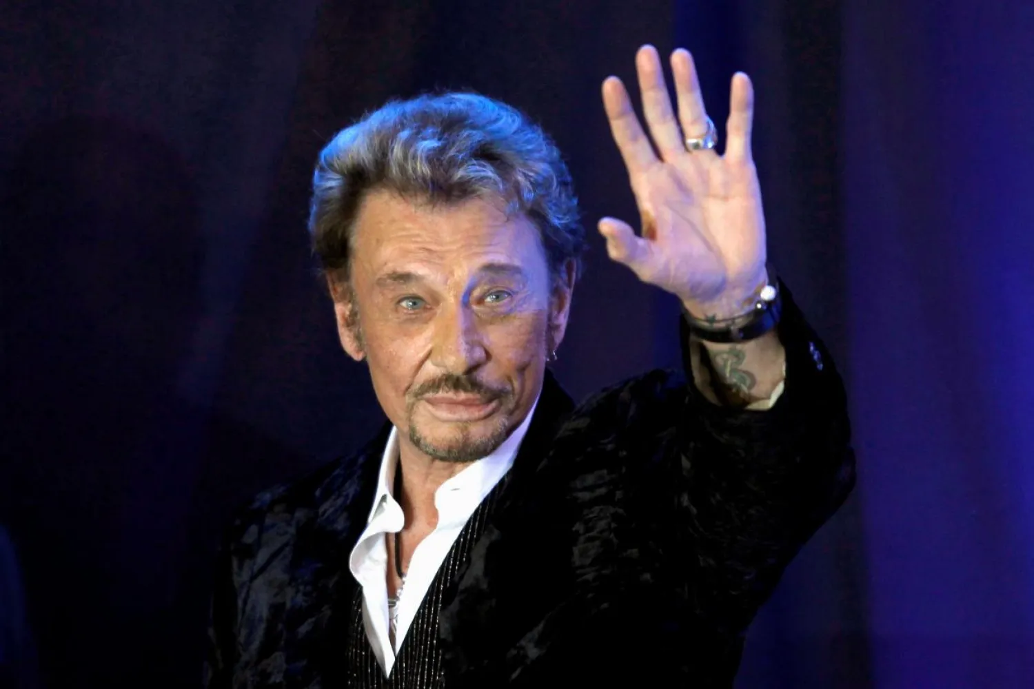 French singer Johnny Hallyday waves to fans attending a ceremony to promote his new album "Jamais seul" (Never alone) at the Virgin Megastore in Paris early March 28, 2011. REUTERS/Charles Platiau/File Photo 