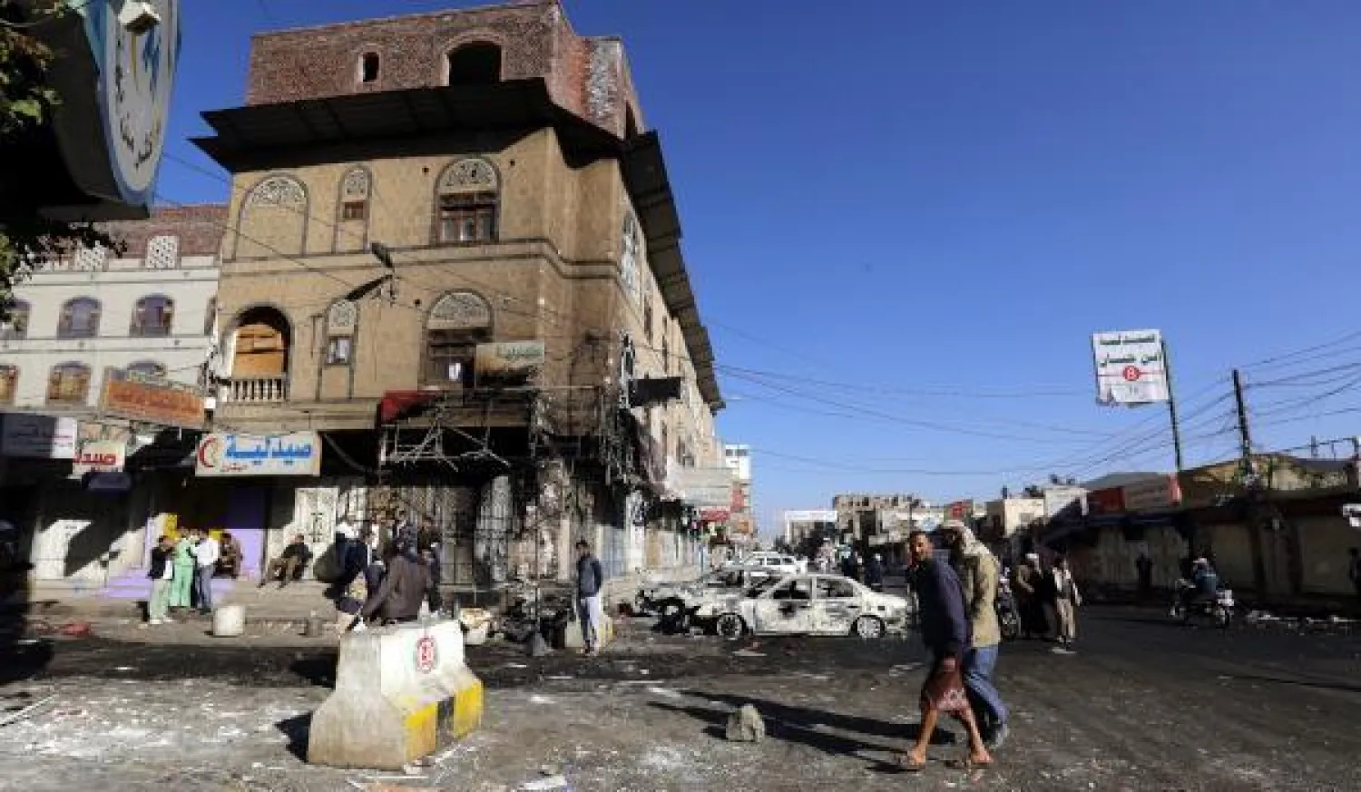 يمنيون يتفقدون الأضرار في أحد شوارع العاصمة صنعاء (إ.ب.أ)