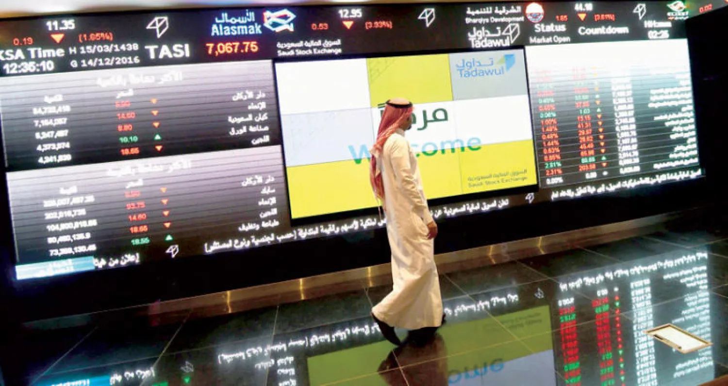 مستثمر سعودي يمر بجانب مؤشر الأسهم في البورصة السعودية (تداول) بالرياض (أ.ف.ب)