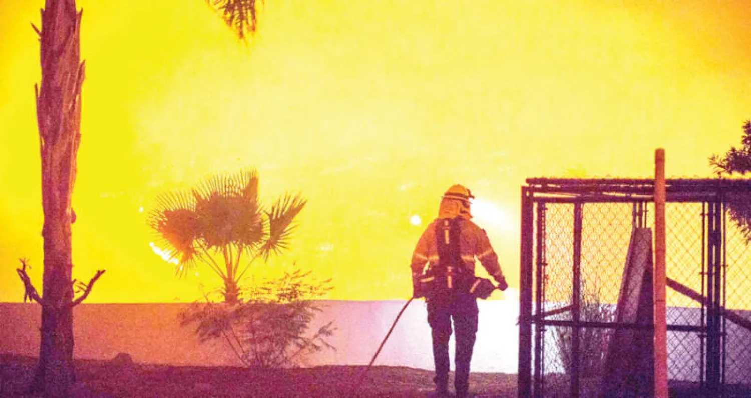 إطفائي يحرس منزلا في بونسال بجنوب كاليفورنيا مع اقتراب النيران منه الليلة قبل الماضية (أ.ف.ب)