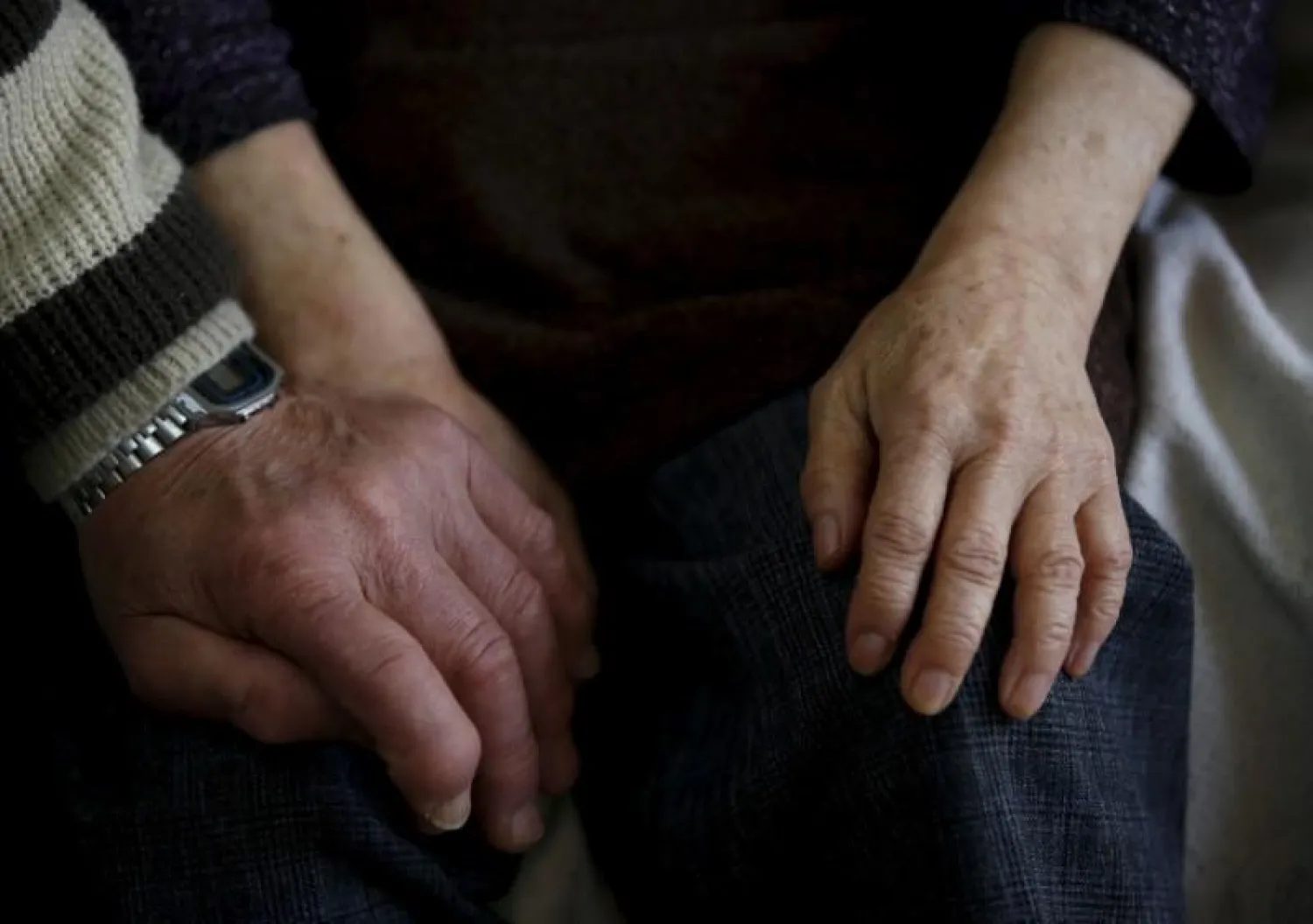 72-year-old Kanemasa Ito (L) holds hands with his 68-year-old wife Kimiko, who was diagnosed with dementia 11 years ago, on a sofa at their home in Kawasaki, south of Tokyo, Japan, April 6, 2016. REUTERS/Issei Kato/File Photo