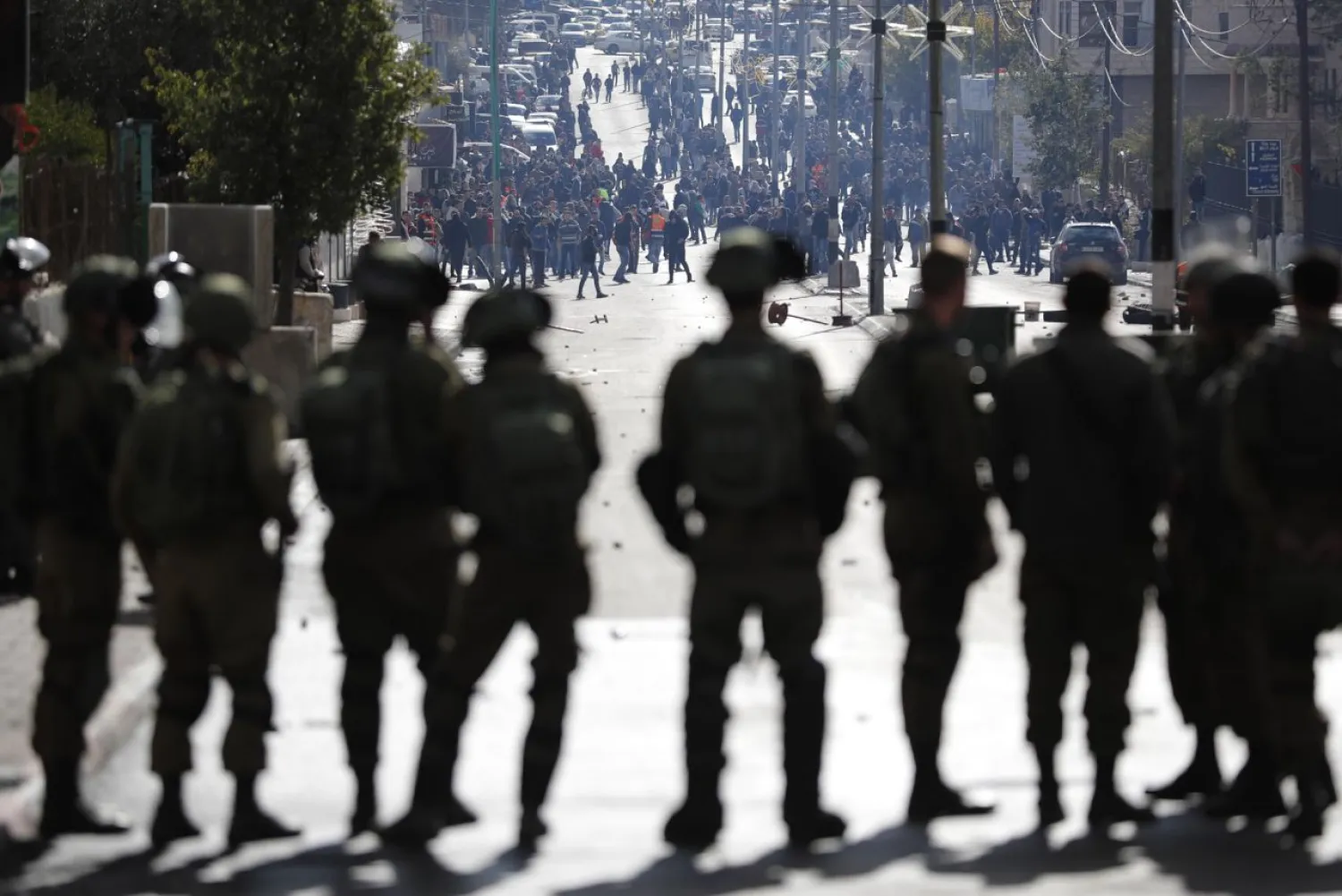 Israeli forces keep watch as and Palestinian protestors throws stones and shout slogans near an Israeli checkpoint in the West Bank city of Bethlehem on December 7, 2017. (AFP)