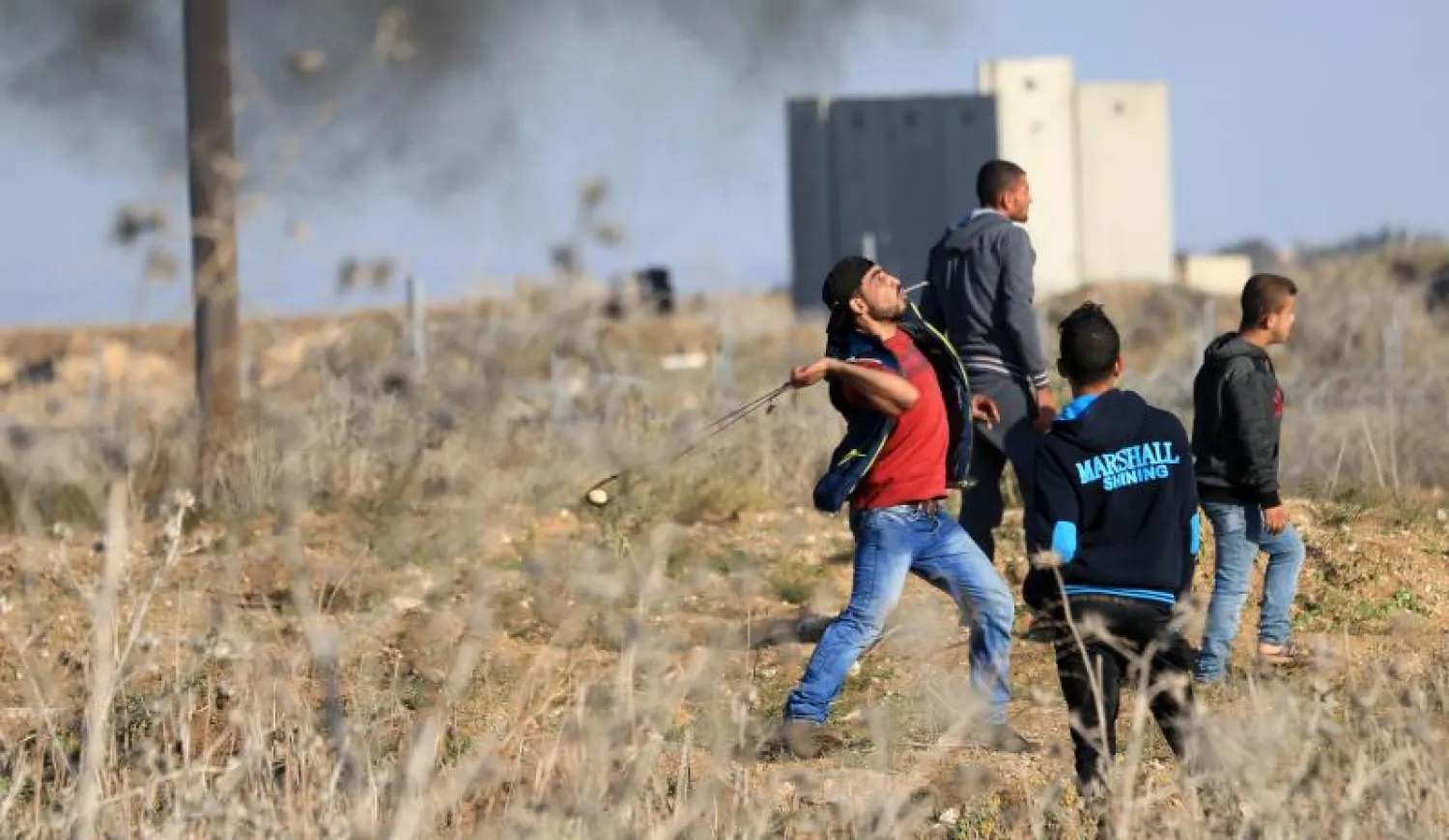 مجموعة من الشباب الفلسطيني يلقون الحجارة علي القوات الإسرائيلية بالقرب من شرق غزة (أ.ف.ب)