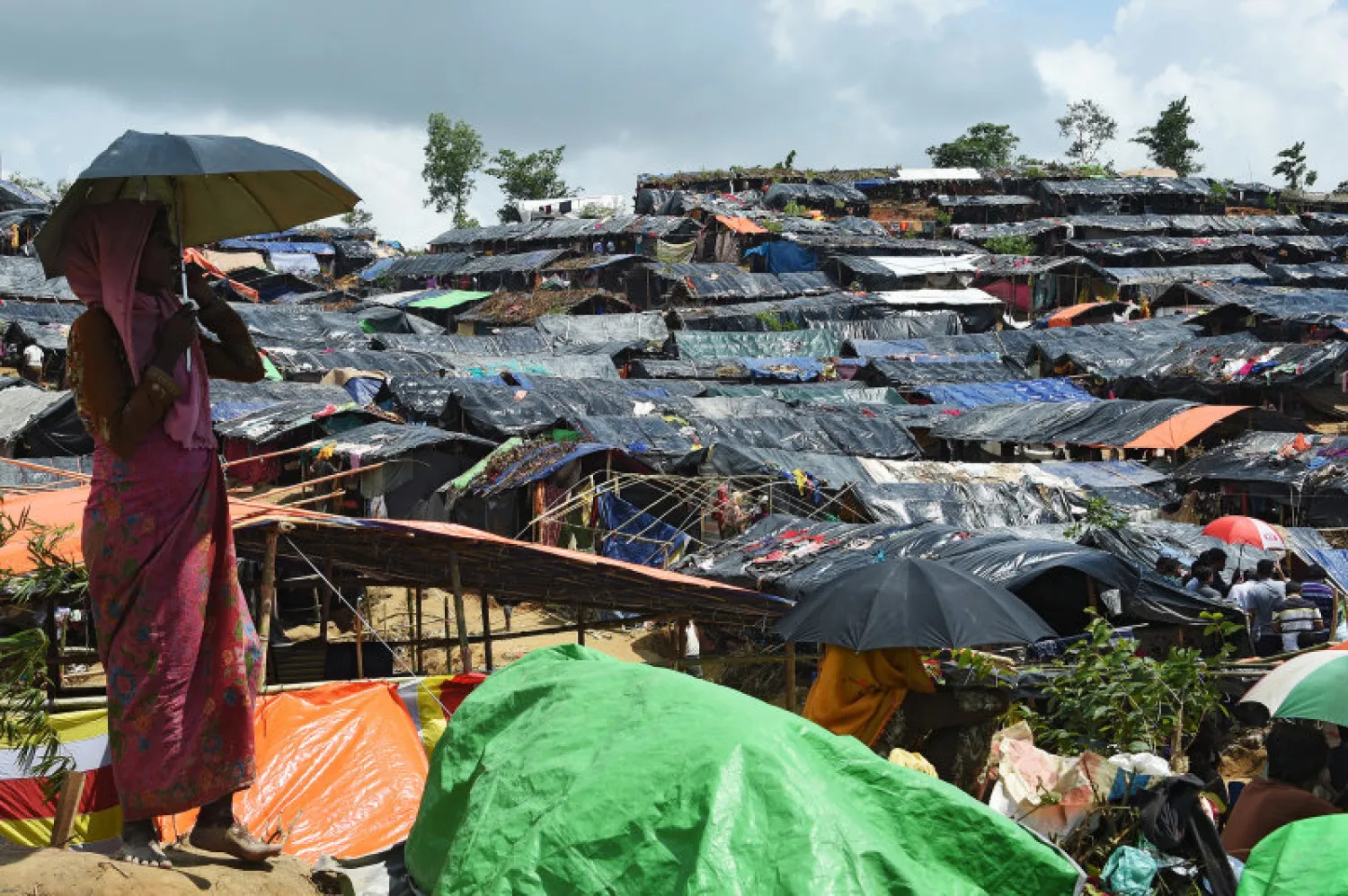 A Rohingya refugee shelters from the sun under an umbrella while looking on at the refugee camp of Balukhali, near the locality of Ukhia on September 21, 2017. (AFP PHOTO / DOMINIQUE FAGET) 