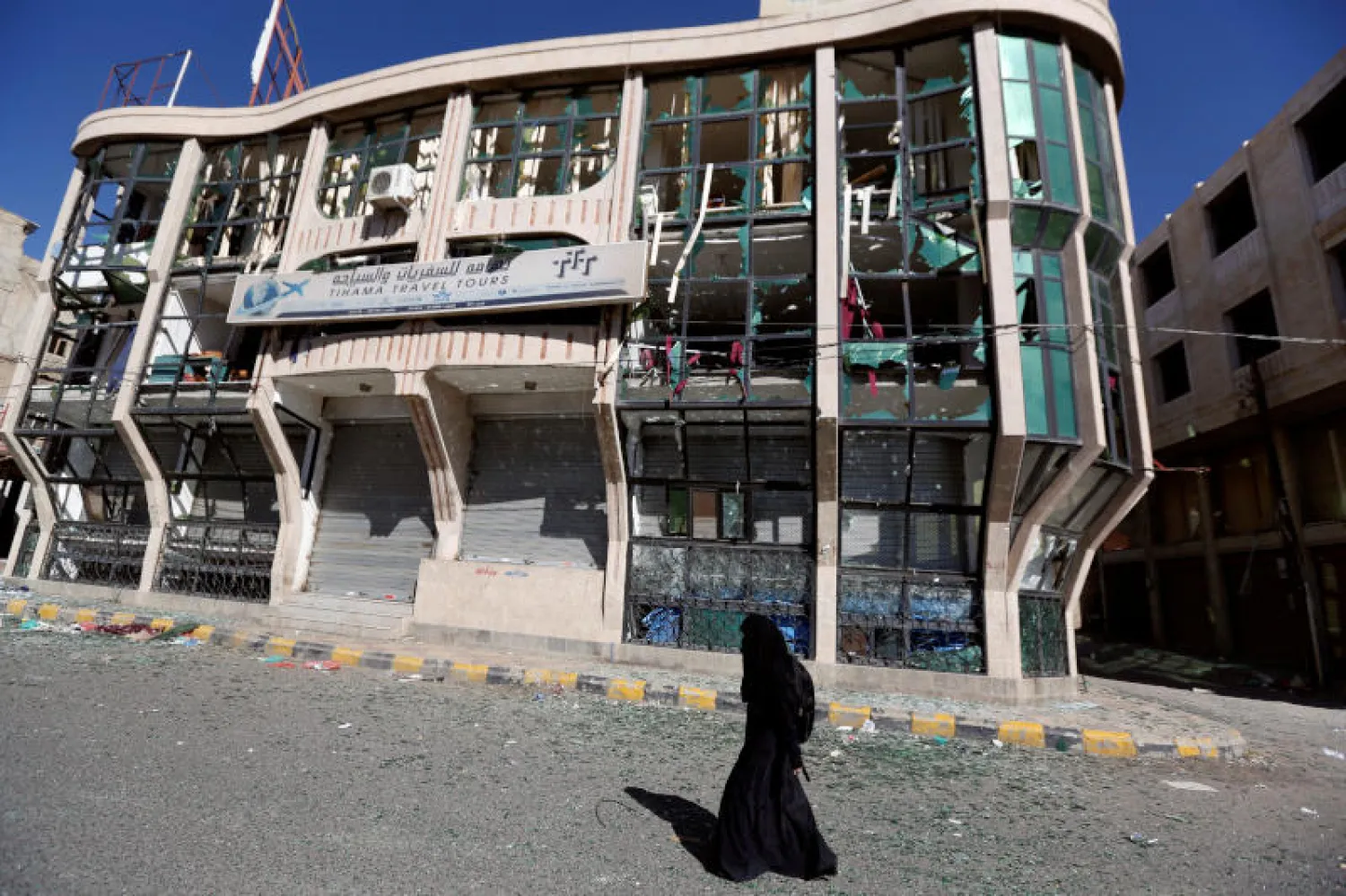 امرأة يمنية تمر بجوار مبنى مدمر جراء الاشتباكات في صنعاء (رويترز)