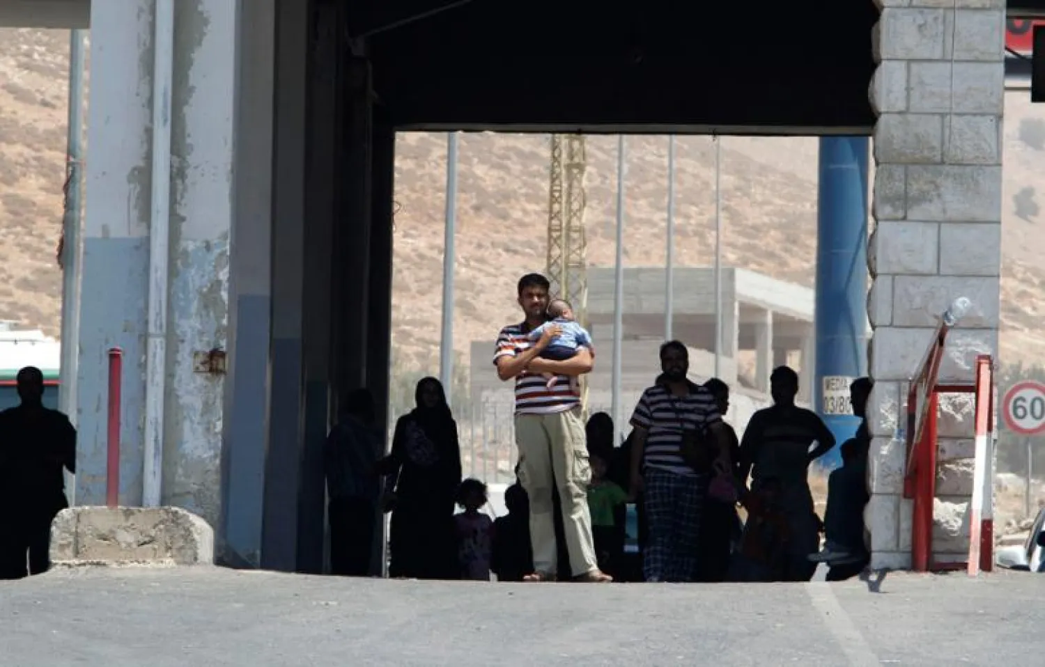 A man walks while holding a baby as Syrian refugees cross the Lebanese-Syrian border of al-Masnaa 20 July 2012. (Photo: Reuters - Mohamed Azakir) 
