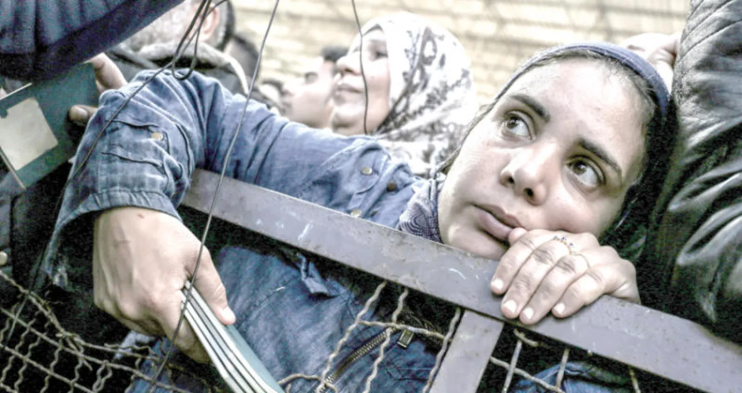 فلسطينية تمسك بجوازات سفر منتظرة الحصول على تأشيرة سفر للعبور إلى مصر من معبر رفح أمس (أ.ف.ب)