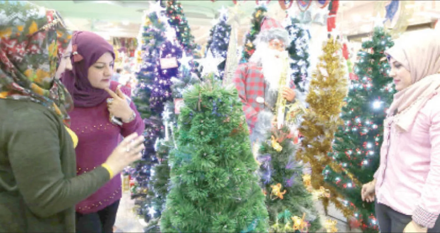 عراقيات في متجر لزينة أعياد الميلاد ورأس السنة في بغداد أمس (أ.ف.ب)