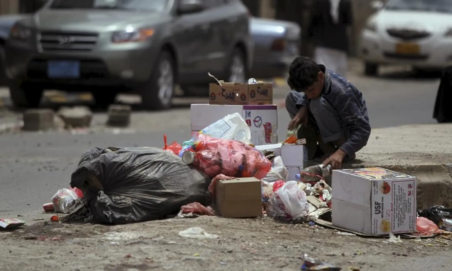 A boy searches for food among litter on a streetside in Sanaa. (Reuters)