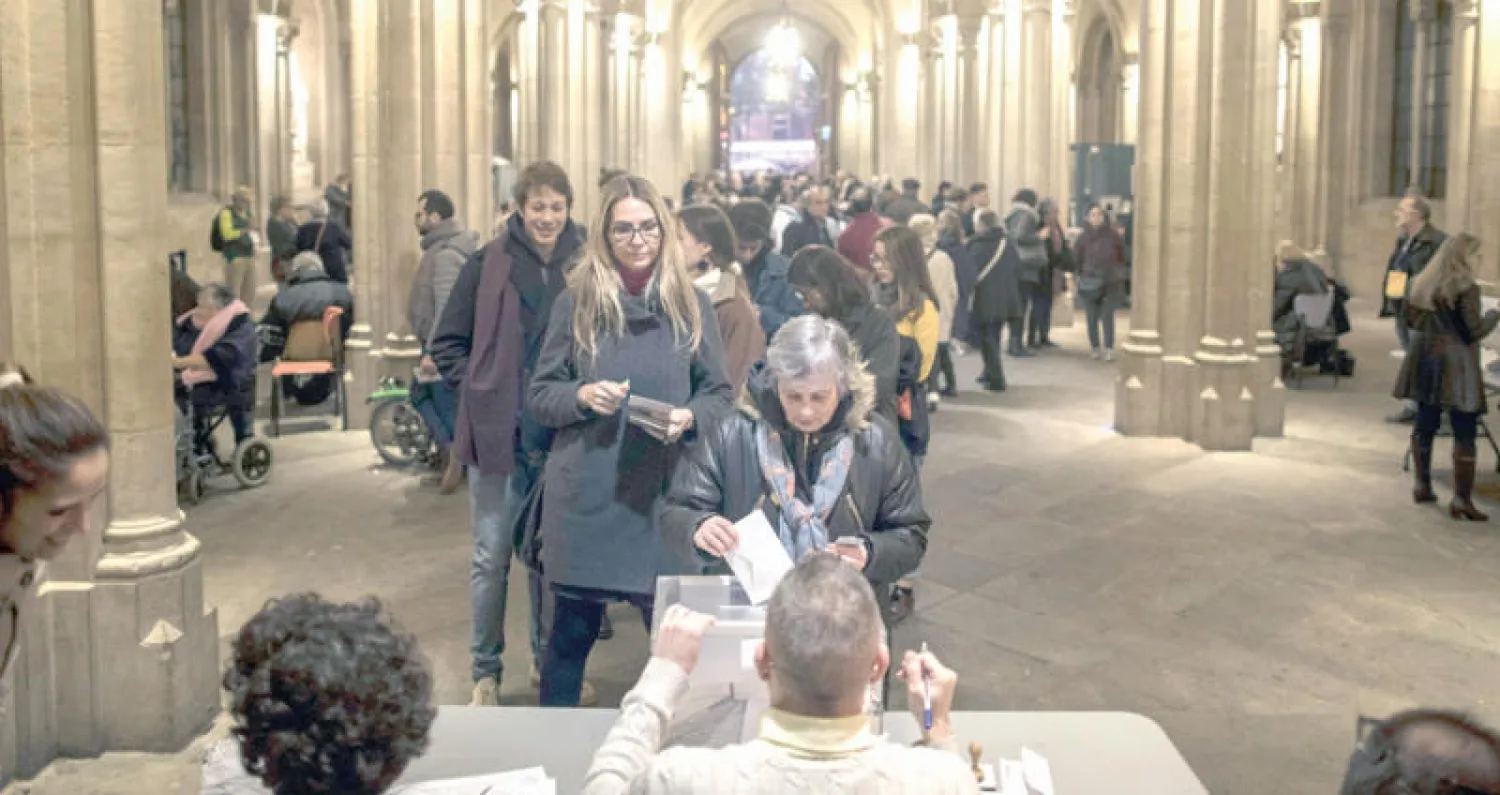 صفوف من الكتالونيين ينتظرون دورهم فيما ناخبة تدلي بصوتها في برشلونة أمس (أ.ب)