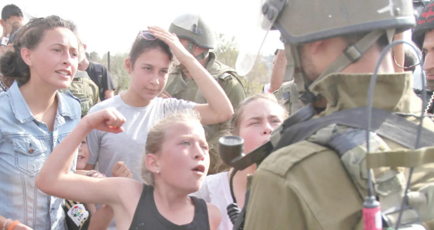 صورة من الأرشيف لعهد التميمي تعود إلى عام 2012 في مواجهة جندي إسرائيلي احتجاجاً على مصادرة أراضٍ في قرية النبي صالح القريبة من رام الله (أ.ف.ب)