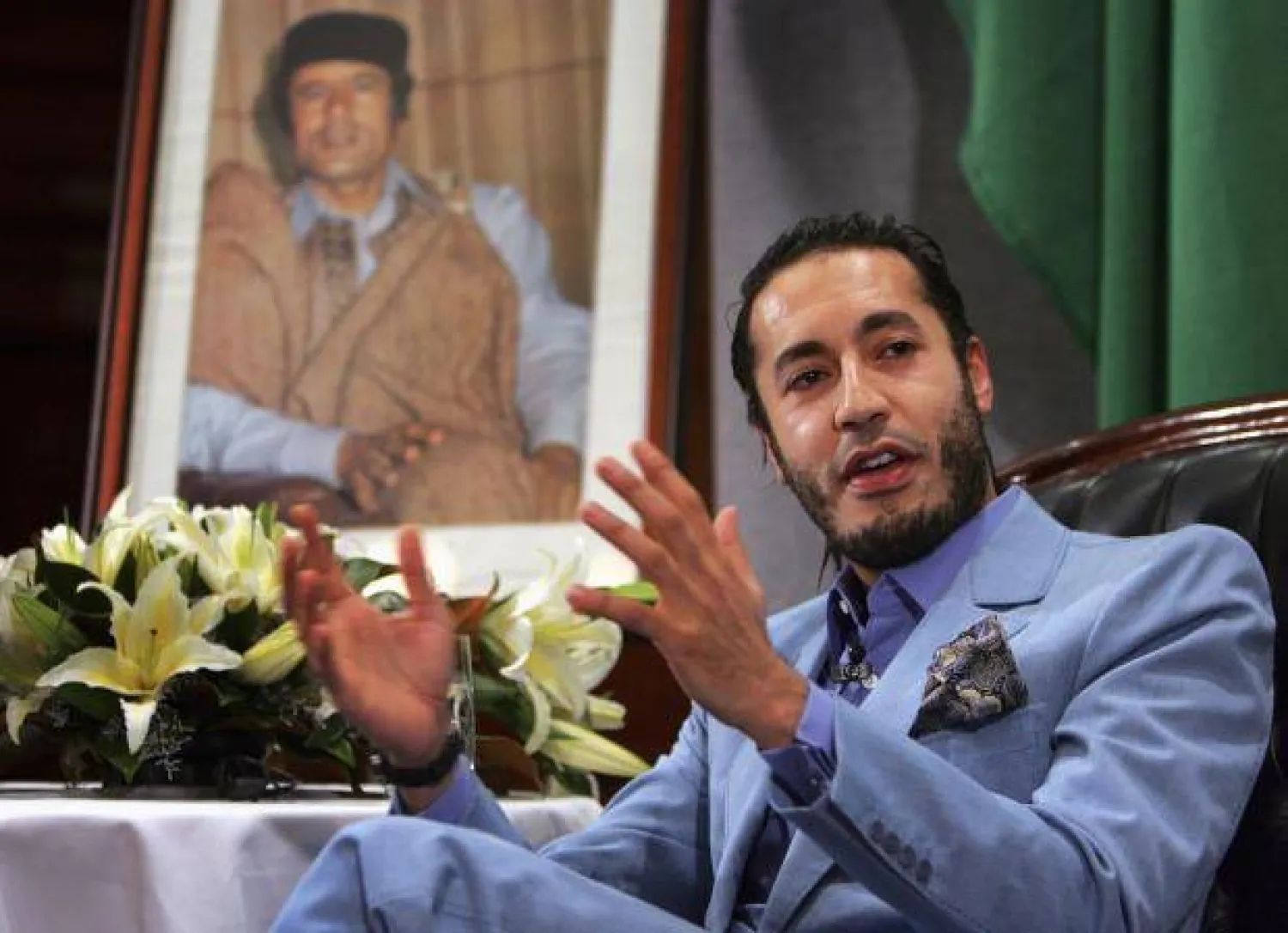 Al Saadi Gaddafi, the third son of Libyan leader Muammar Gaddafi (portrait on left), speaks at a news conference in Sydney in this February 7, 2005 file photo Reuters
