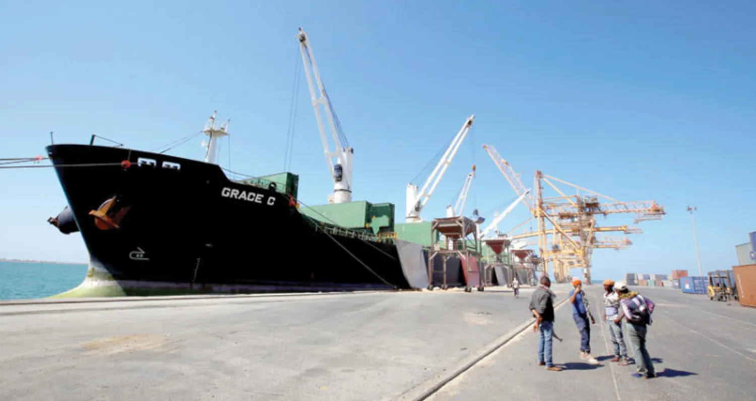 عمال ينظرون إلى سفينة تفرغ حمولتها في ميناء الحديدة أمس (رويترز)