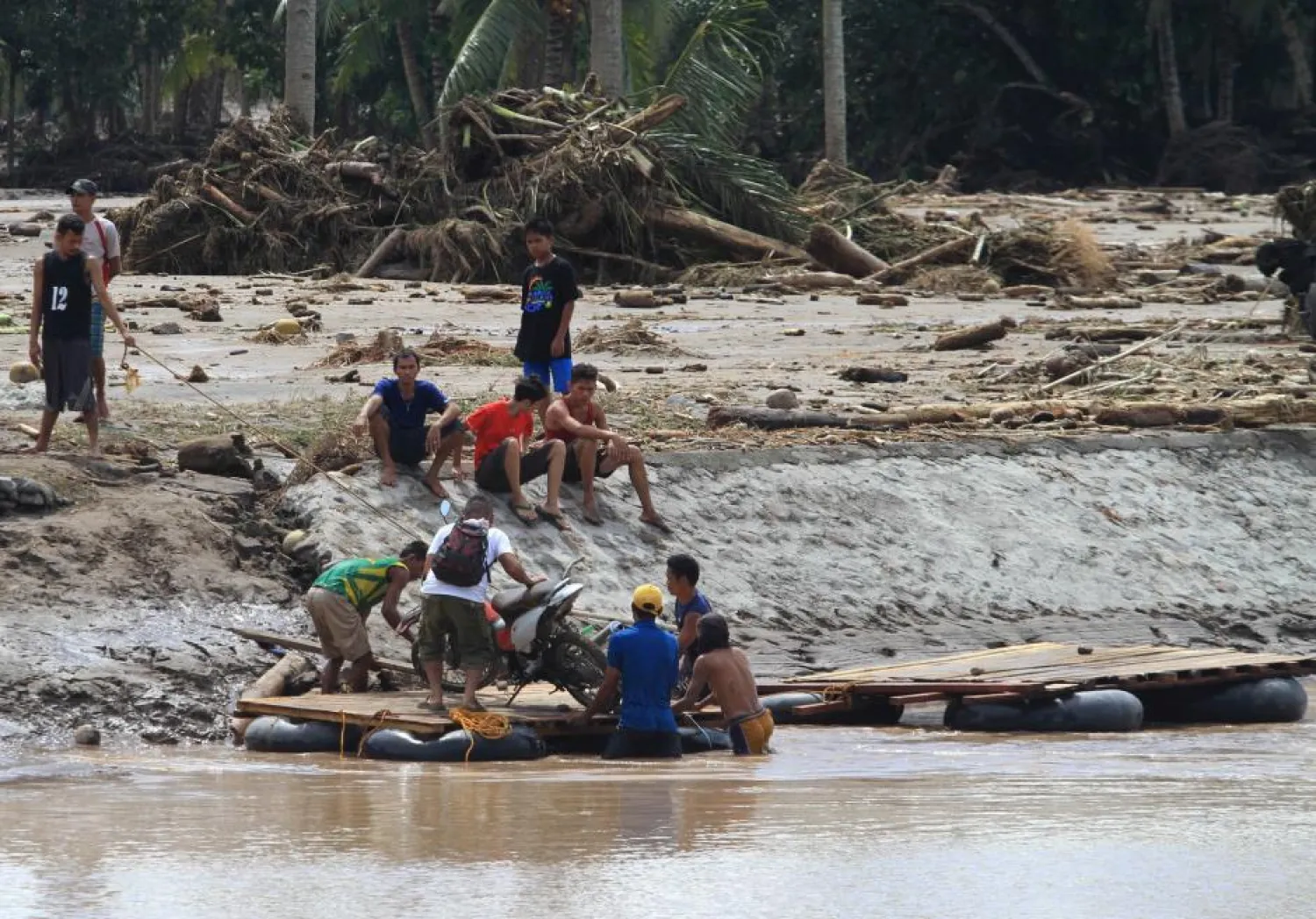 A man and his motorcycle are transported on a makeshift raft, after a bridge was destroyed by flash floods in southern Philippines, December 23, 2017. (Reuters)