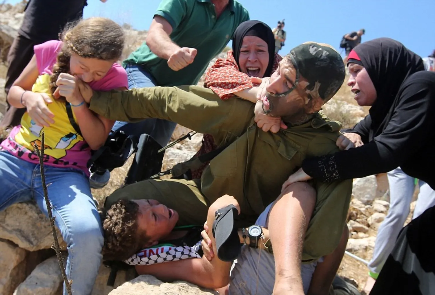 Palestinian teenager Ahed al-Tamimi bites the hand of an Israeli soldier as he holds her brother, Mohammed, in a chokehold during an attempted arrest in 2015. (AFP)