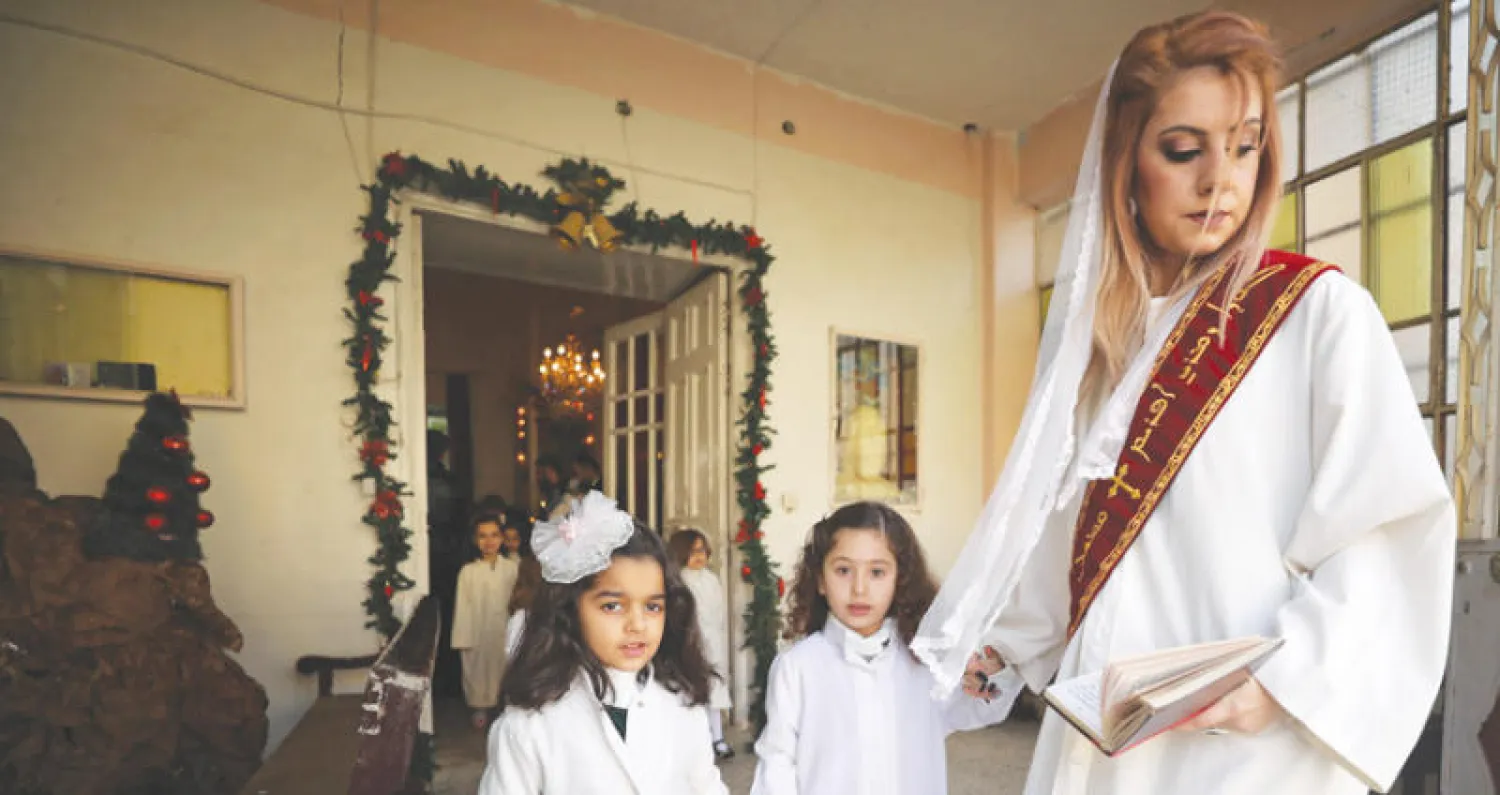 سورية سريانية من القامشلي تشارك مع طفلتيها في احتفالات أعياد الميلاد أمس (رويترز)