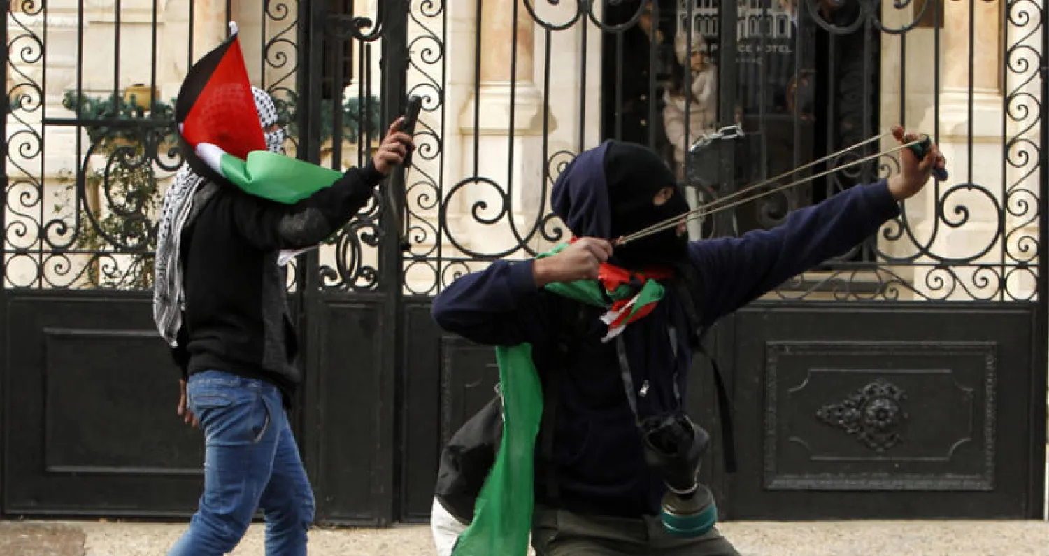 شبان ملثمون في بيت لحم يستخدمون «النقيفة» (النبلة) في رشق جنود الاحتلال بالحجارة (أ.ف.ب)