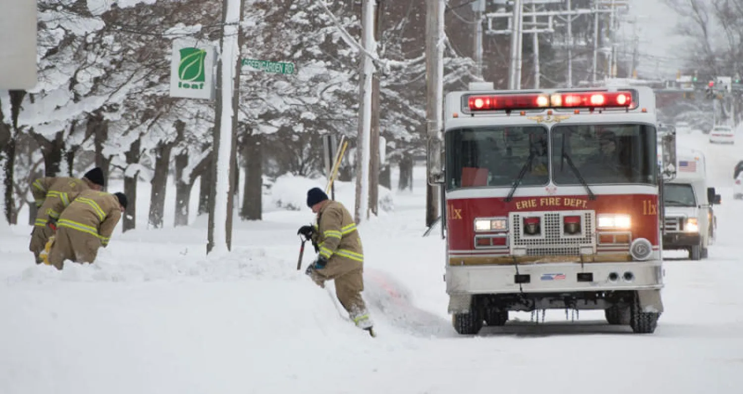 رجال الإطفاء يزيلون الثلوج من حول صنابير المياه في الشارع الثامن في مدينة أري بولاية بنسلفانيا (روترز)