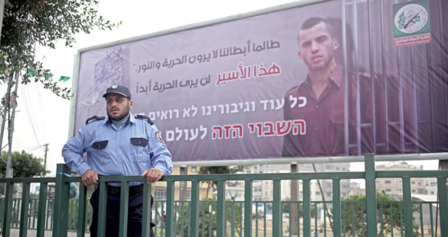 عنصر من «حماس» أمام صورة الجندي الأسير في غزة أمس (إ.ب.أ)