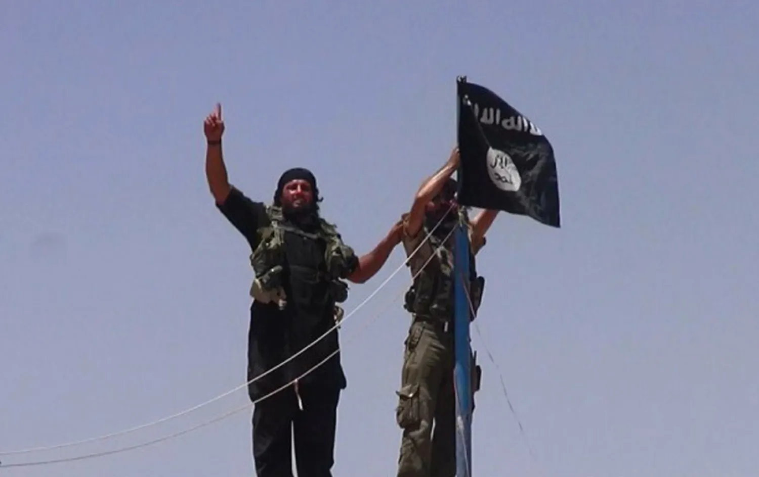  ISIS Militants hanging their flag on a pole at the top of an ancient military fort after they cut a road through the Syrian-Iraqi border. (AFP)
