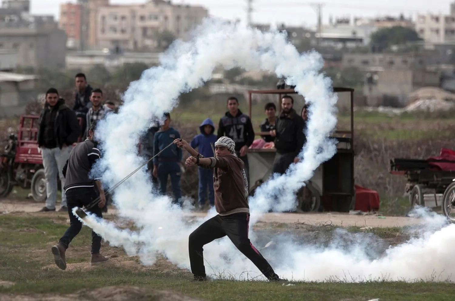 A Palestinian protester uses a sling to throw a teargas canister towards Israeli soldiers during clashes on the Israeli border with Gaza, December 22, 2017. (AP)