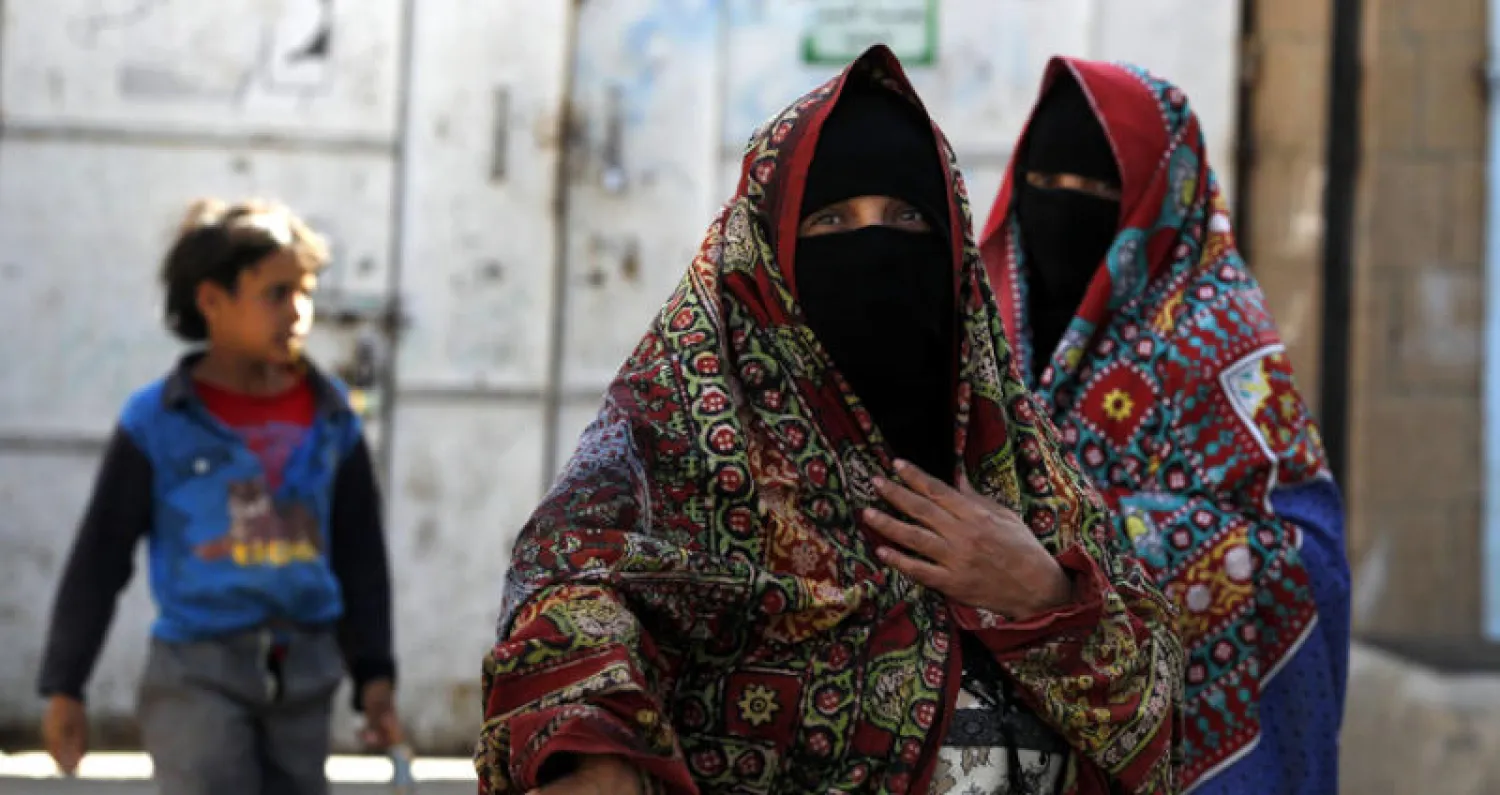 يمنيتان تقفان قرب جمعية خيرية في صنعاء (إ.ب.أ)