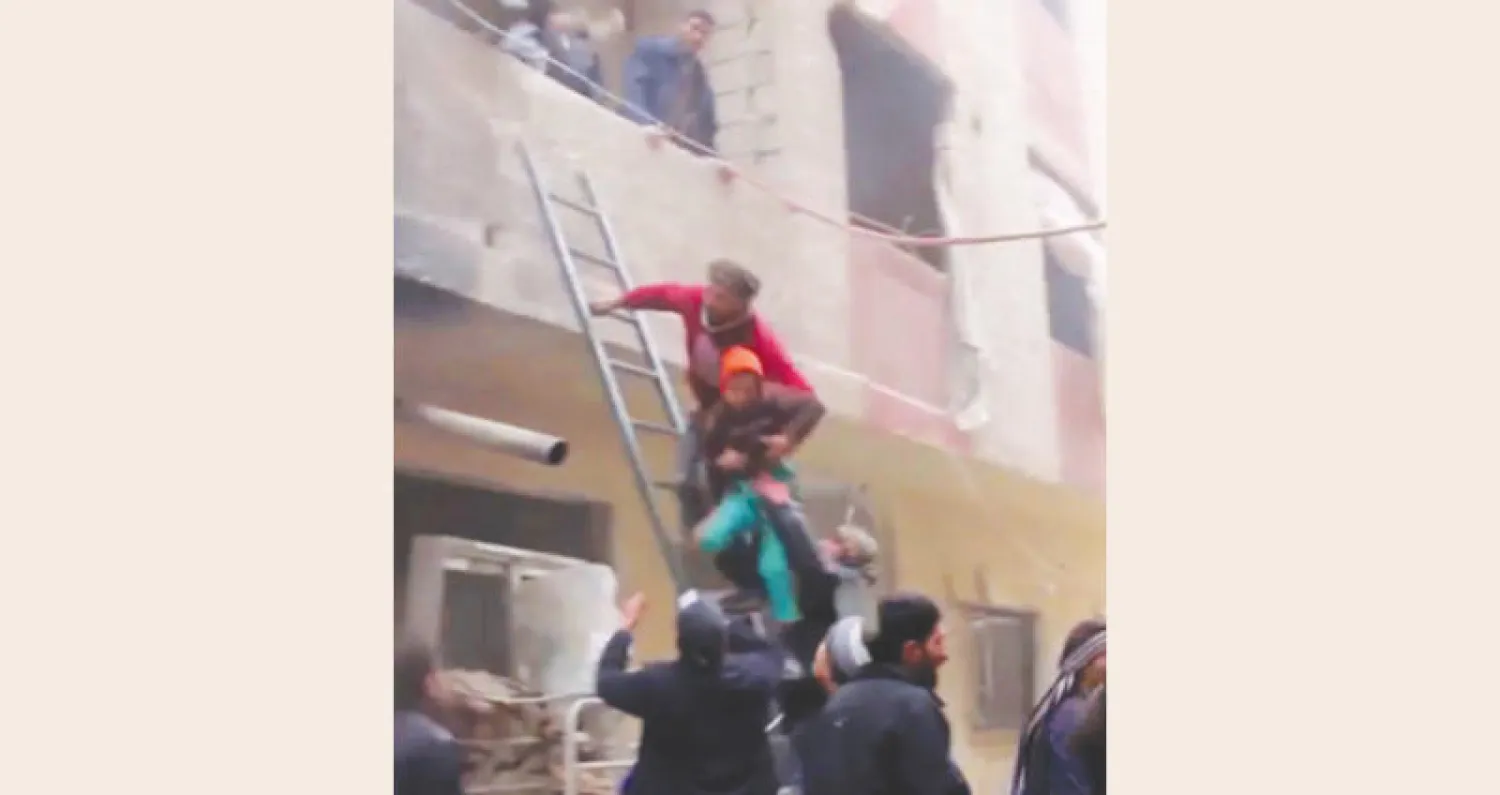 صورة مقتطعة من فيديو لإنقاذ مدنيين من بيت بعد استهدافه بالطيران الحربي في مسرابا قرب دمشق أمس (أ.ب)