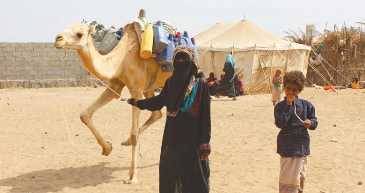 نازحة من الحديدة تقود جملاً محملاً بحاجياتها لدى وصولها برفقة صبي إلى مخيم للنازحين في عدن أمس (أ.ف.ب)
