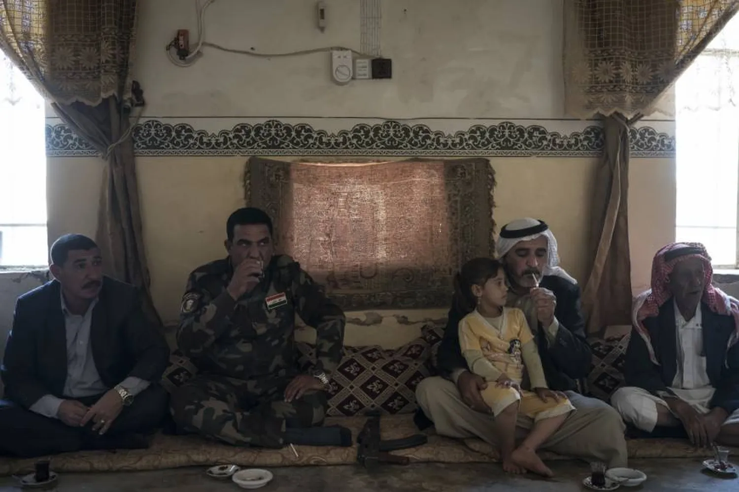  A local fighter and residents gather Nov. 12 at the mayor's home in the Bijwaniya village, south of Mosul, Iraq. PHOTO: AP