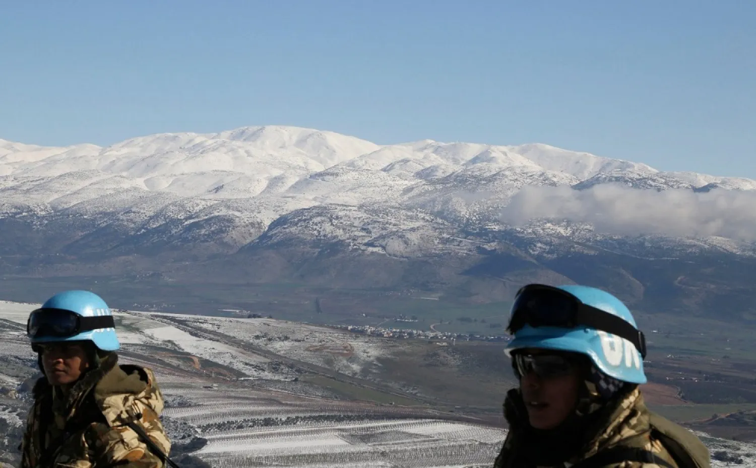 UNIFIL peacekeepers stand in front of snow-covered mountains in Kfar Kila village near the Lebanese-Israeli border, in south Lebanon. (Reuters)