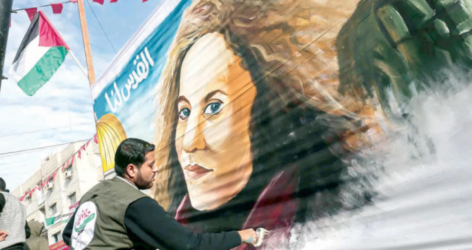 علم فلسطين أعلى زاوية لوحة لفنان فلسطيني في رفح تحمل وجه عهد التميمي وقبة الصخرة وعبارة «القدس لنا» (أ.ف.ب)