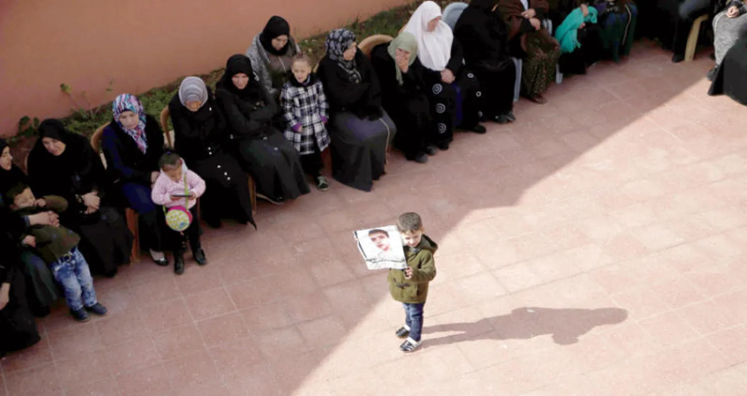 طفل فلسطيني يرفع صورة للفتى مصعب التميمي (17 عاماً) الذي قتلته قوات الاحتلال قبل يومين (أ.ف.ب)
