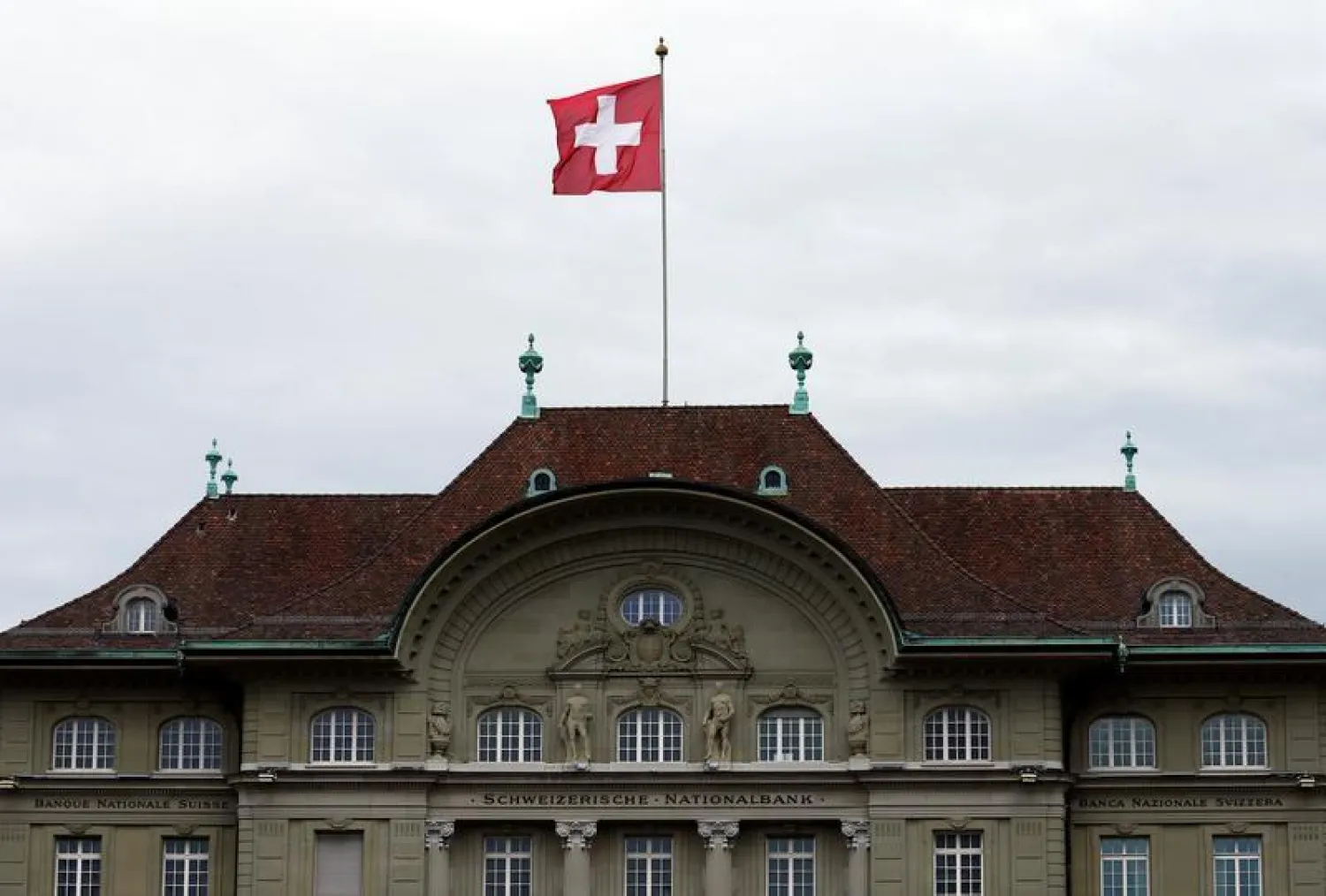 A Swiss national flag flutters in the wind atop the Swiss National Bank SNB headquarters in Bern, Switzerland April 16, 2015. REUTERS/Ruben Sprich/File Photo