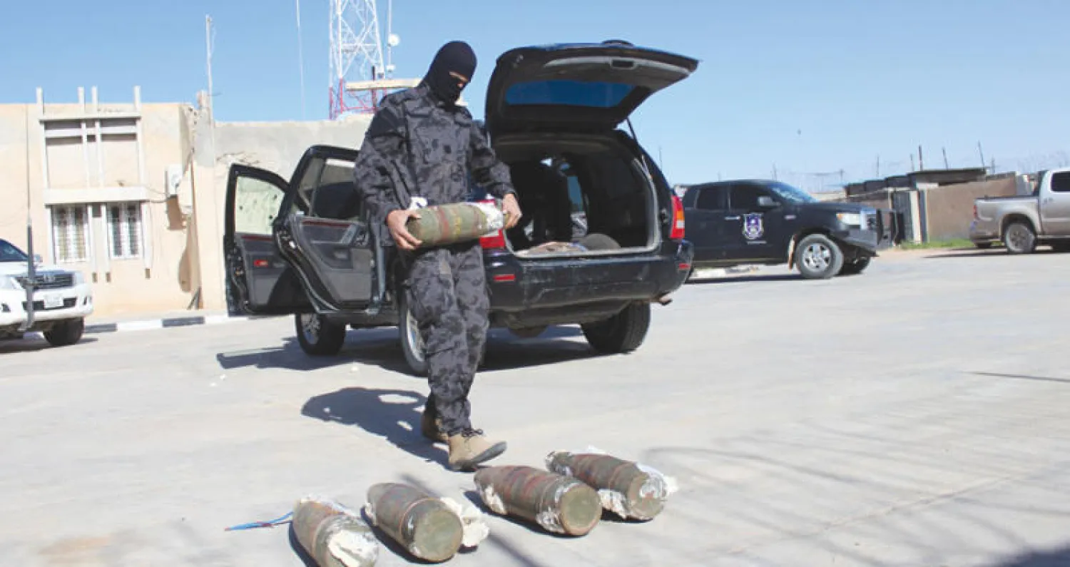 رجل أمن ليبي يحمل مواد متفجرة عثر عليها في سيارة مفخخة بمصراتة أمس (رويترز)