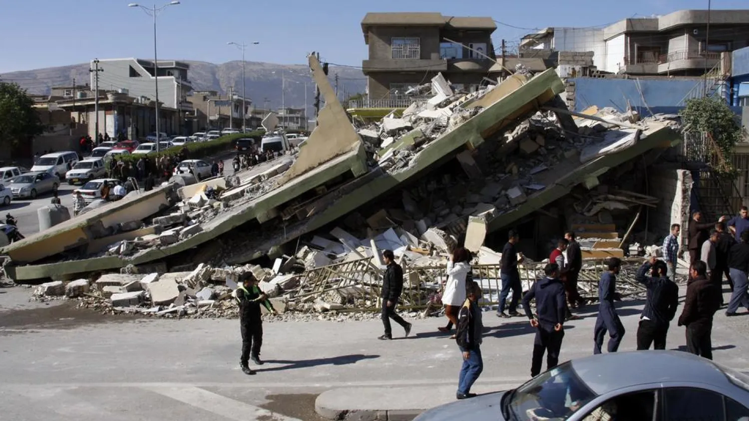 People gather around a leveled building in the mountainous town of Darbandikhan in Iraqi Kurdistan on November 13, 2017, following a 7.3-magnitude quake that hit the Iraq-Iran border area. Shwan Mohammed / AFP 
