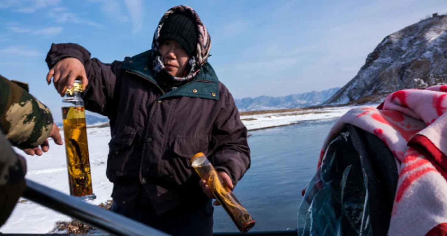 بائع كوري شمالي... وبعض المتاجر بين البلدين أغلقت أبوابها بسبب العقوبات المفروضة والتي التزمت بها بكين (أ.ف.ب)