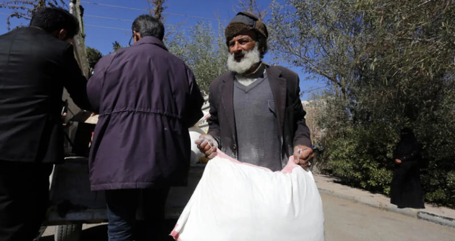 مسن يمني يحمل مساعدات غذائية في صنعاء (إ.ب.أ)