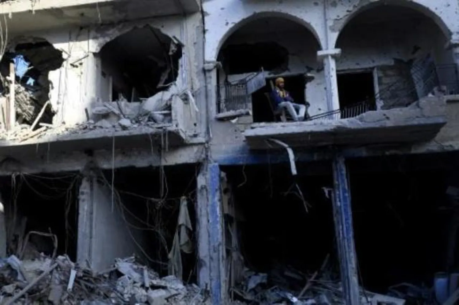 رجل يجلس بشرفة مبنى مدمر في الرقة السورية التي استعادها مقاتلون غالبيتهم من الأكراد من أيدي تنظيم داعش الإرهابي (أ.ف.ب)
